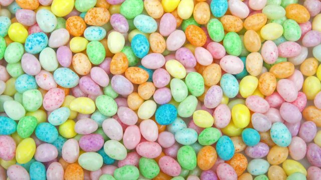 HD video zooming in on background of colorful candy jelly beans on flat surface. Popular Easter candy.
