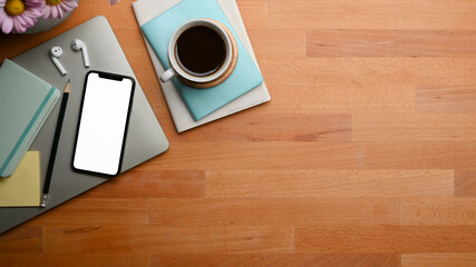 Wooden table with smartphone and stationery, laptop, coffee cup and copy space