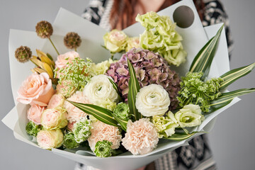 Beautiful bouquet of mixed flowers in womans hands. the work of the florist at a flower shop. Delivery fresh cut flower. European floral shop.