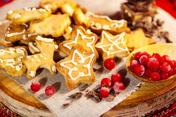 Christmas gingerbread cookies, chocolate and frozen berries, on a wooden stand, red background, large depth of field, selective focus. Christmas and New Year concept.