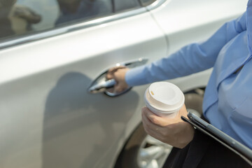 hand of  businesswoman hand hold cup of coffee and tablet and right hand  opening a car door.