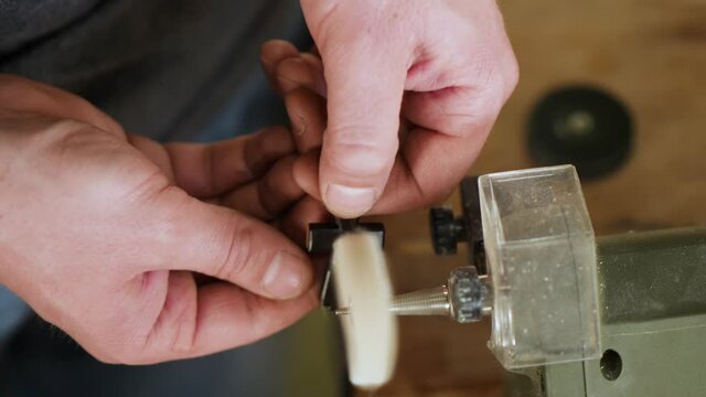 artisan polishes a wooden ebony cross on a machine. carved ebony cross