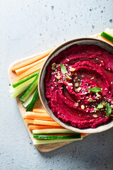 beet hummus in a ceramic bowl on a light background, top view