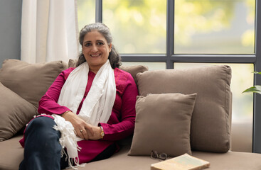 A HAPPY SENIOR ADULT WOMAN SITTING AND LOOKING AT CAMERA	