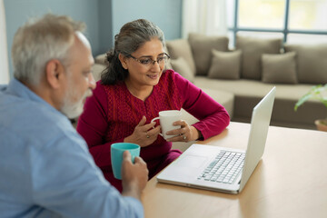 Fototapeta premium A SENIOR ADULT WOMAN AND HUSBAND LOOKING AT LAPTOP TOGETHER 