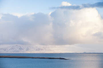Icelandic coastal landscape. Snowy mountains and clouds