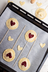 The process of baking small cherry pies on sticks on Valentine's Day. Raw cherry pie pops © Natalia_Inspired