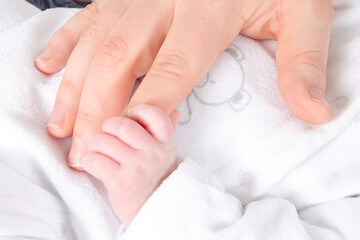 Newborn baby touching his mother hand closeup detail