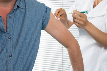 Cleaning up patient arm for a vaccine man injection with a syringe at hospital