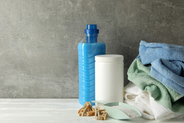 Detergent, powder and towels on wooden table against gray background