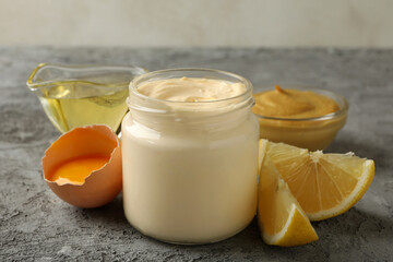 Jar with mayonnaise and ingredients for cooking on gray background