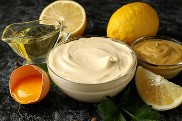 Bowl with mayonnaise and ingredients for cooking on black smokey background