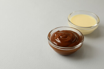 Bowls with condensed milk on gray background