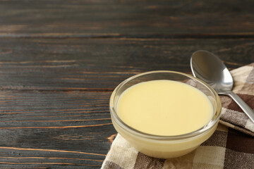 Towel, spoon and bowl with condensed milk on wooden background