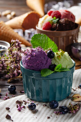 Three scoops of Vanilla pistachio and chocolate icecream balls in clay bowls on wooden kitchen table