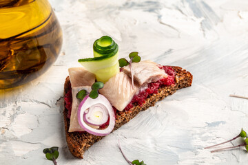 sandwich with herring fillets, onion, cucumber, cucumber, onion on rye bread. traditional street food in norway, close-up. Delicious breakfast or snack on a light background, top view