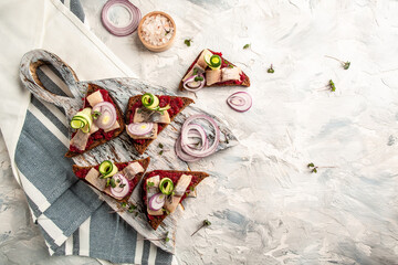 Rye Bread Sandwich Smorrebrod with Herring, beetroot salad, green cucumber, onion and microgreen. Toast with herring fillet. Scandinavian cuisine