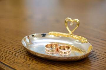 two gold wedding rings lie on a metal tray