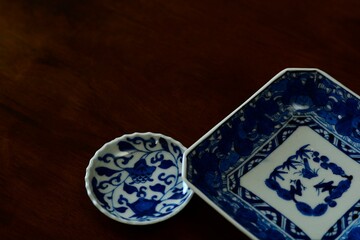 picture plate. This is a very fine example of Japanese traditional. lay out  vintage ceramic “ imari ware ”. This antique walnut table is made in England.wooden background. soft focus image.