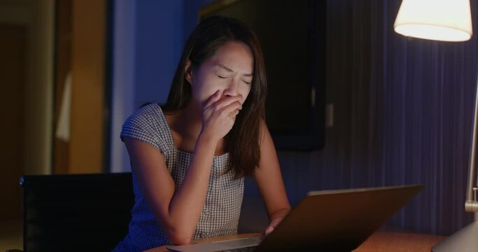 Woman feel sleepy and work on laptop computer at night