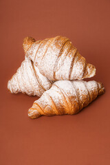 Tasty buttery croissants in the brown background. 