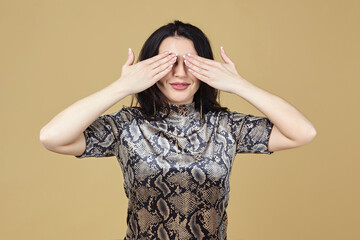 the brunette covered her face with her hands. photo shoot in the studio on a yellow background