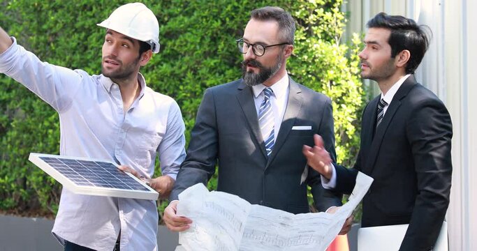 Hipster business man and Office building owner and energy engineer plan a project to build a solar panel for the building under construction. clean and green alternative energy concept.