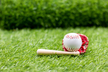 Baseball is on green grass with bat and glove