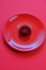 Red jelly dessert in a red round plate on a bright red background .  dietary low calorie vegetarian dessert. Vegan dessert. Low Calorie Diet Sweets