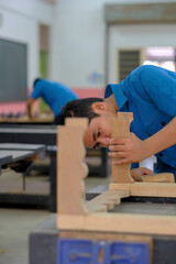 Young carpenters in work clothes assambling components of console table in workshop.