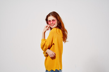 cheerful pretty woman wearing pink glasses and holding her hair smile yellow sweater close-up