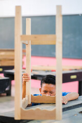 Obraz premium Young carpenter in work clothes assambling components of console table in workshop.