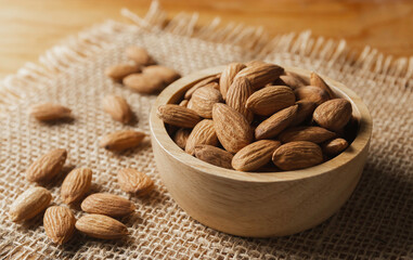 Closeup almonds in wooden bowl on sackcloth almond concept with copy space.