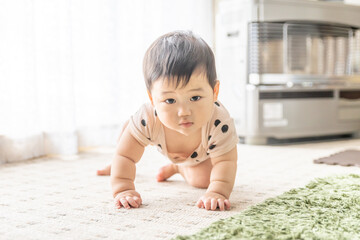 Fototapeta premium リビングの窓辺でお座りやはいはいをする赤ちゃん