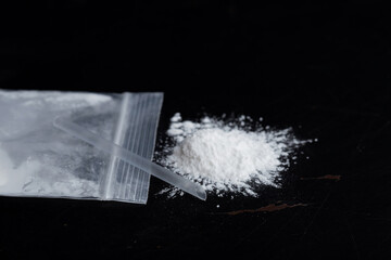 ketamine drugs and plastic straw on bag of white powder on black wood background.Drug epidemic...