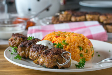 Ground beef skewer with serbian djuvec rice and yogurt sauce on a plate
