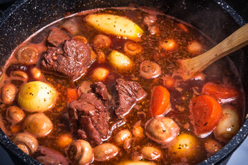 Cooking Burgundy beef in a saucepan on the stove close-up.