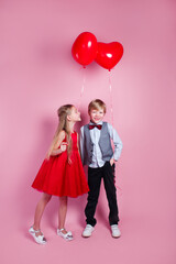 Valentines day. Little girl kissing boy on pink background. Children with heart balloons