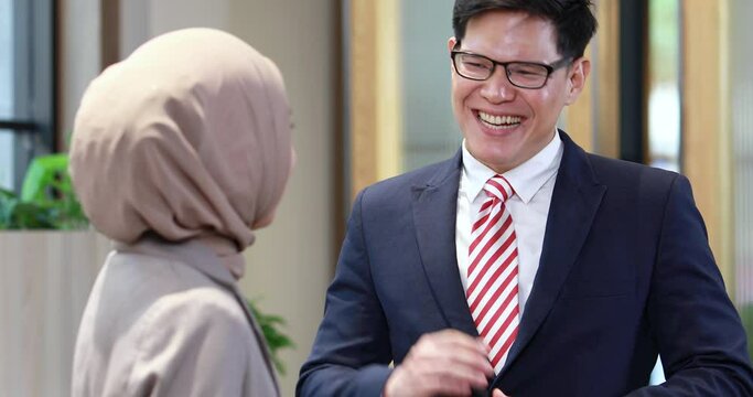 Young business muslim woman and business man colleague walking and discussing outside the office. Woman is holding a coffee and businessman is holding a digital tablet outdoor.