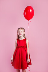 Valentines day. Little girl in red dress with heart shape air balloon on pink background