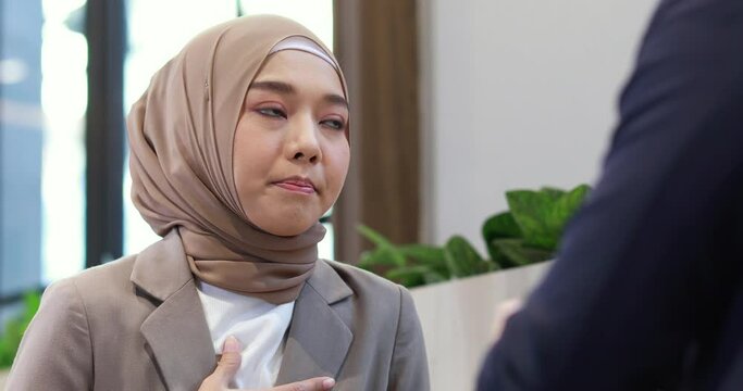 Young business muslim woman and business man colleague walking and discussing outside the office. Woman is holding a coffee and businessman is holding a digital tablet outdoor.
