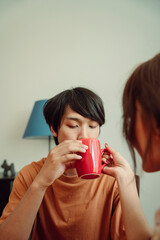 Asian thai couple drinking coffee or water from cup in dinning room.