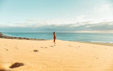 Fototapeta na wymiar Woman walking in the desert till a point overlooking the sea, leaving footprints in the sand
