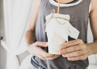 Woman hand is holding coffee cup with straw made from sugar product on near window of cafe.