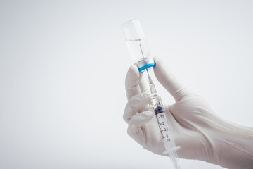 Doctor or scientist in laboratory holding a syringe with liquid vaccines for injection on medical...