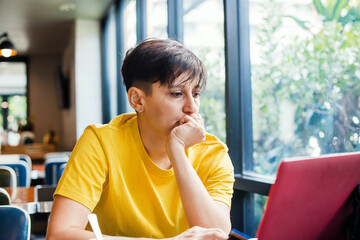 Young woman in trendy yellow colored t-shirt working on computer. Colors of the year 2021.