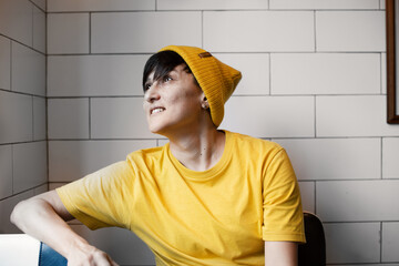 Young hipster woman in yellow hat and shirt is sitting in Barbershop.