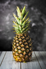 Pineapple on dark background on wooden table © Exploder