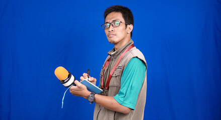 asian male journalist wear vest and ready writting for news isolated blue background