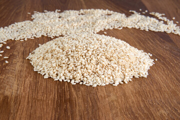 Close up of organic raw white sesame seeds on wooden background